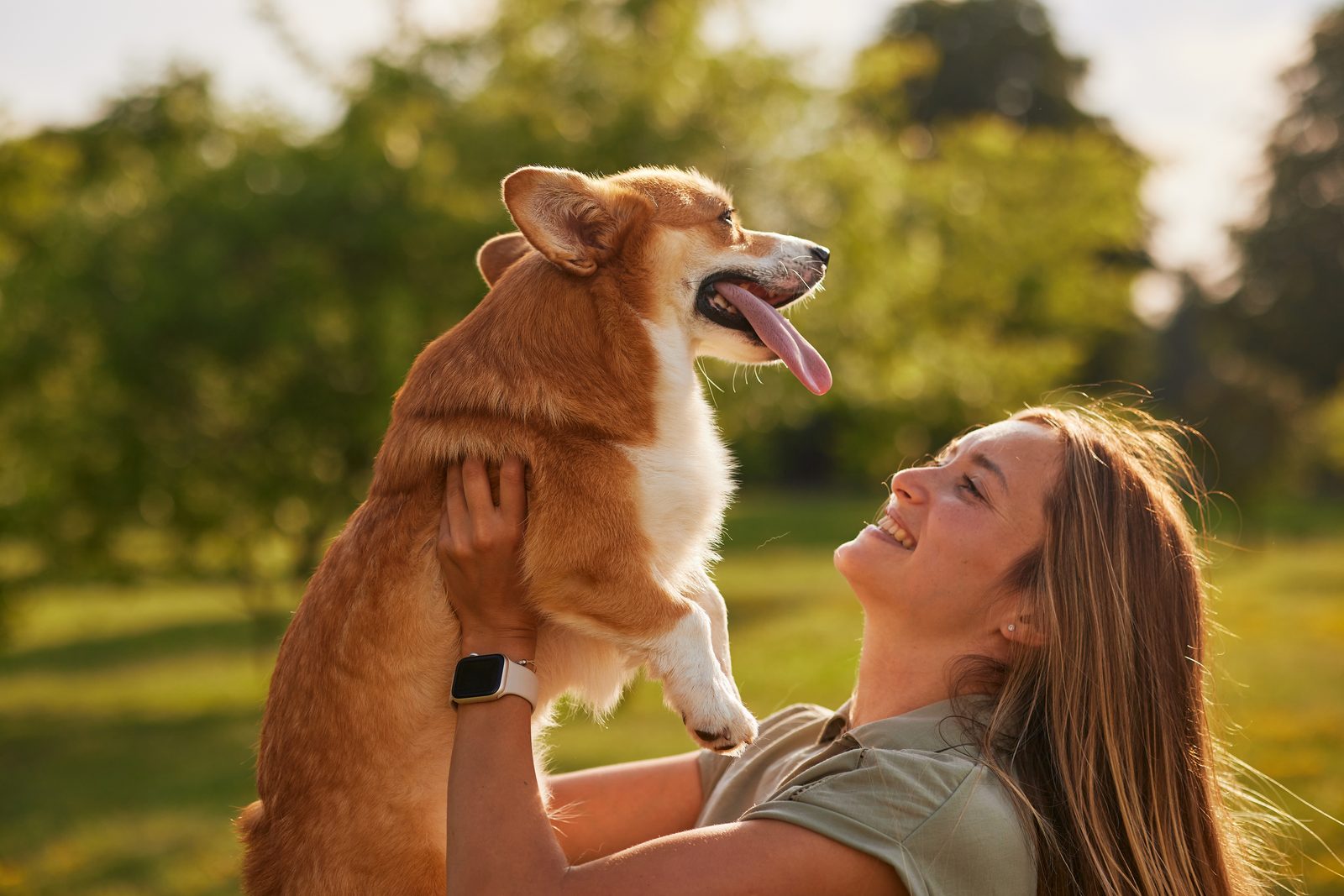 A girl hugging a corgi in the park